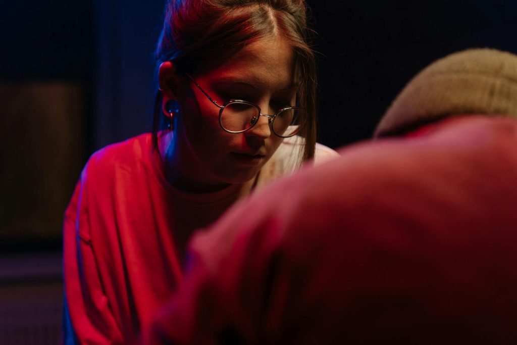 Woman in a dimly lit tattoo studio with neon lights creating a vibrant atmosphere.