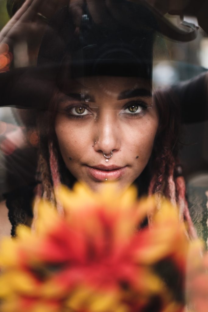 femme avec chapeau noir et chemise à fleurs jaunes et rouges